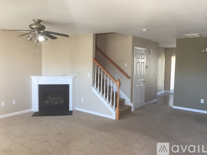 A living room with a fireplace and a ceiling fan.
