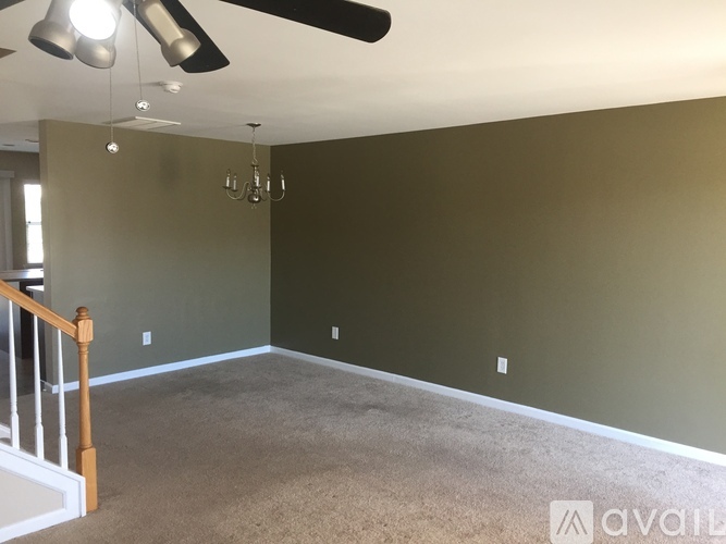 A room with a carpeted floor and a chandelier hanging from the ceiling.