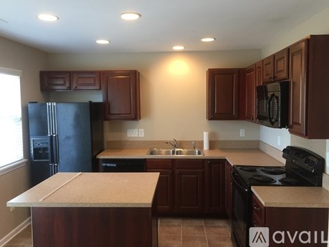 A kitchen with brown cabinets and a black refrigerator.