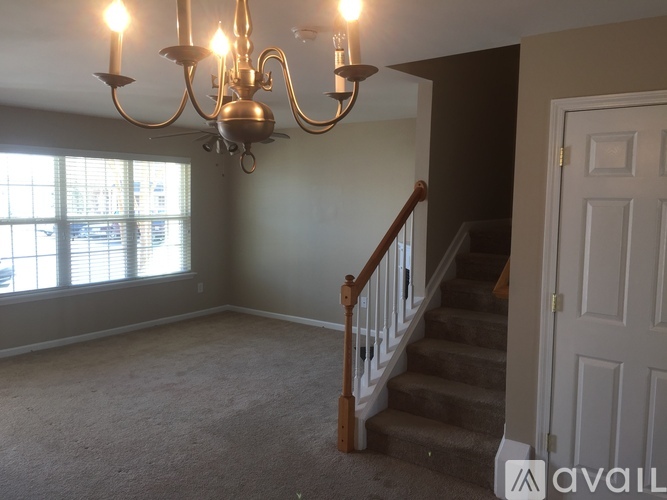 A chandelier hangs over a staircase in a room with a window.