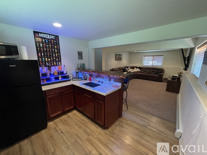A kitchen with a black refrigerator and wooden cabinets.