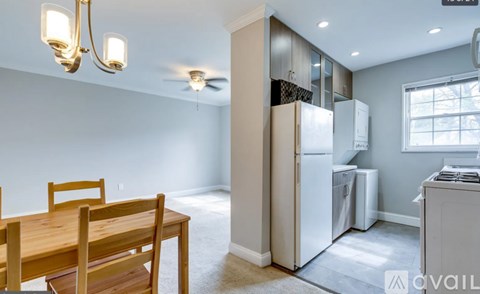 A kitchen with a table and chairs in the foreground and a refrigerator and oven in the background.