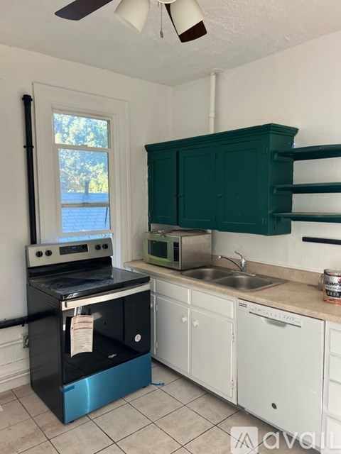 A kitchen with a black stove top oven and a green cabinet.