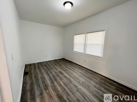 A room with wooden flooring and a window with blinds.