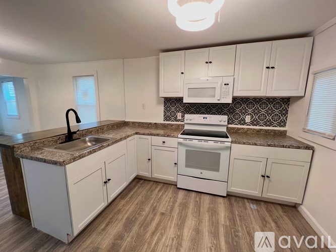 A kitchen with white cabinets and a granite countertop.