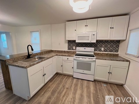 A kitchen with white cabinets and a granite countertop.