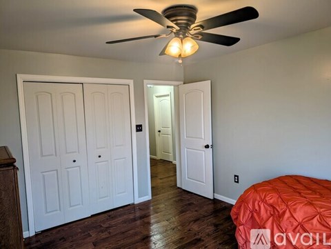 A bedroom with a bed, a ceiling fan, and two doors.