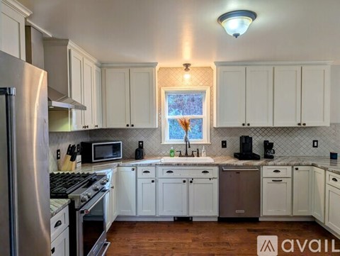 A kitchen with white cabinets and a stainless steel refrigerator.