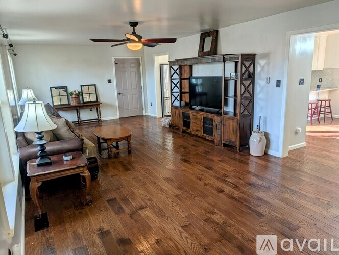 A living room with a wooden floor and a television on a stand.
