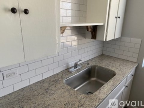 A kitchen with a sink and white cabinets.