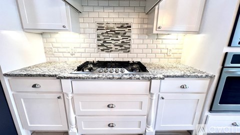 A kitchen with white cabinets and a granite countertop.