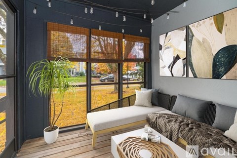 A living room with a couch, a plant, and a painting on the wall.