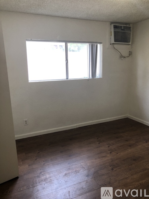 A room with wooden floors and a window with blinds.