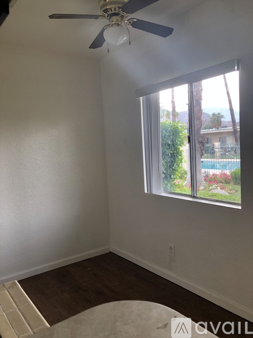 A room with a ceiling fan and a window overlooking a pool.