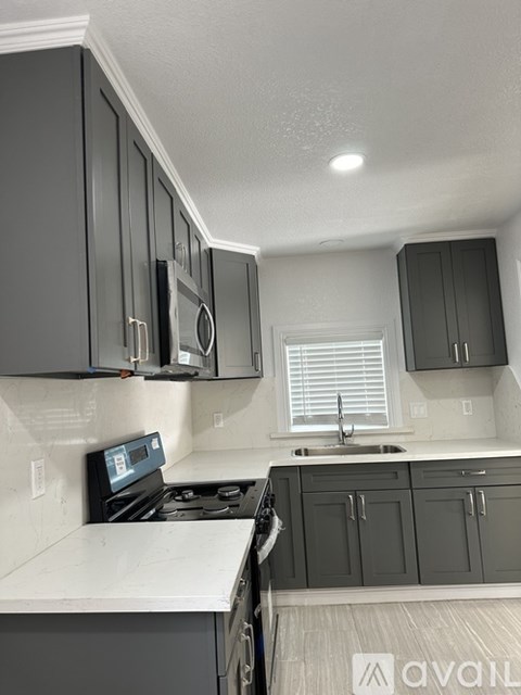 A kitchen with dark grey cabinets and white countertops.