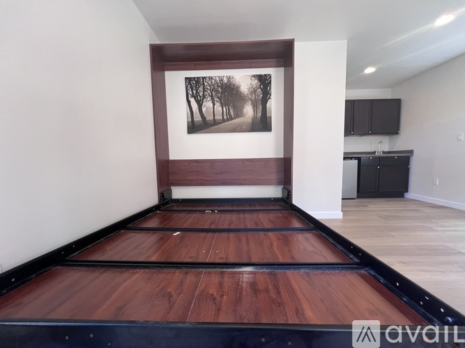 A room with a wooden floor and a painting of trees on the wall.