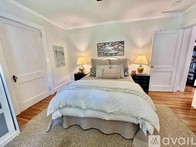 A bedroom with a large bed and two lamps.