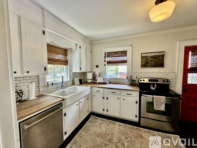 A kitchen with white cabinets and a red door.