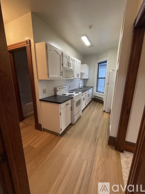 A kitchen with wooden floors and white cabinets.