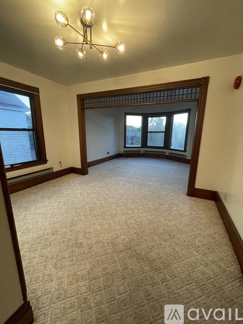 A room with a carpeted floor and a chandelier hanging from the ceiling.