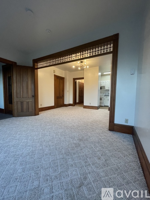 A spacious room with a carpeted floor and a wooden door.