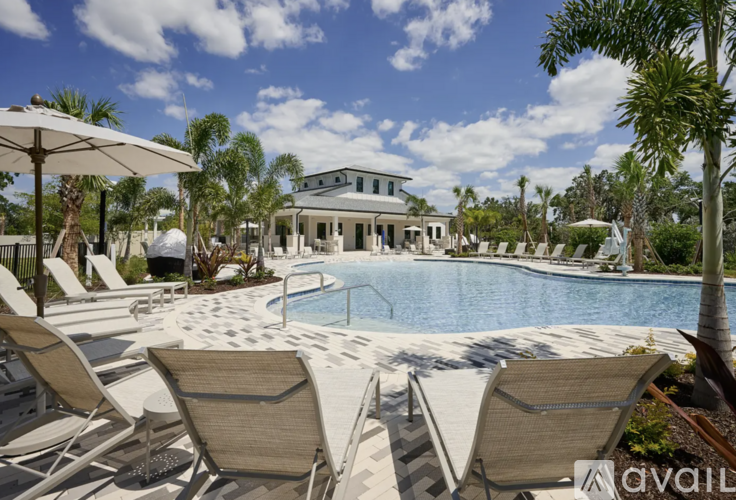 A pool area with chairs and umbrellas in front of a house.
