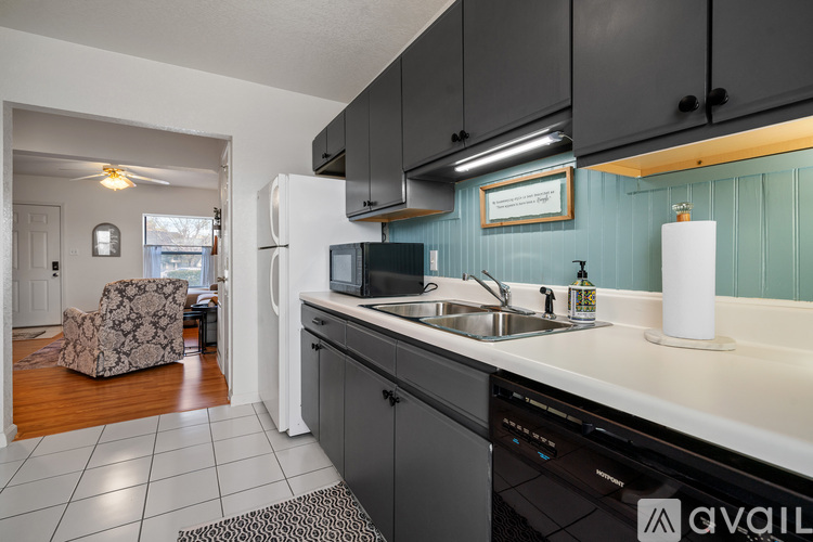 A kitchen with black cabinets and a white refrigerator.