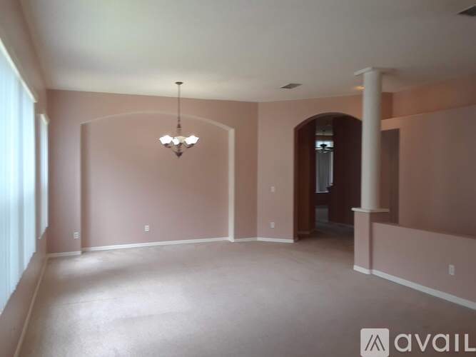 A spacious room with a chandelier and a door on the right side.