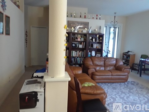 A living room with a brown leather couch and a white column.