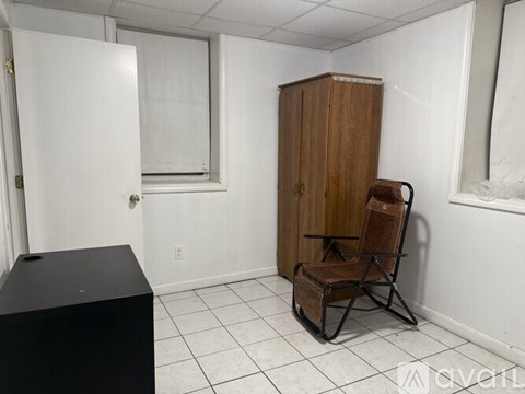 A room with a black box, a wooden cabinet, and a rocking chair.