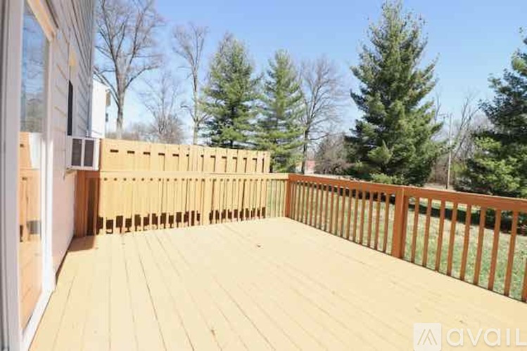 A wooden deck with a railing and trees in the background.