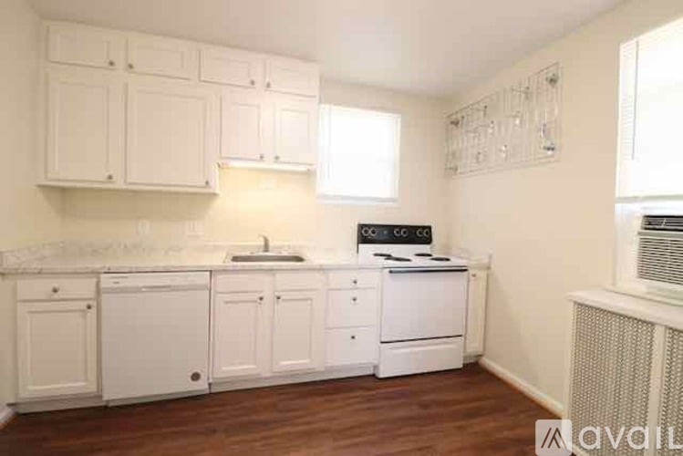 A kitchen with white cabinets and a wooden floor.