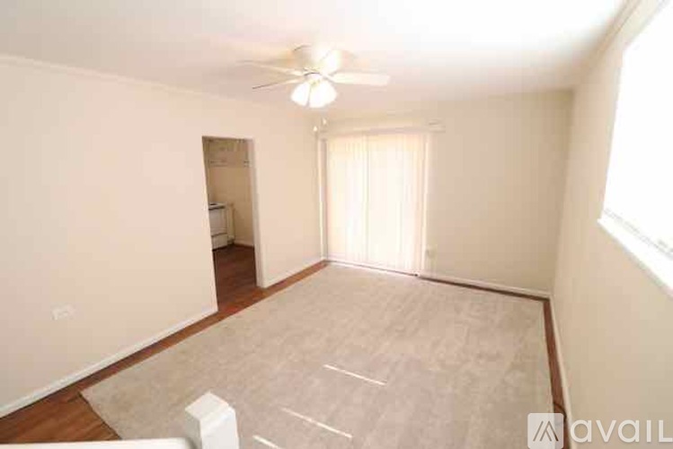 A spacious room with a ceiling fan and a rug on the floor.
