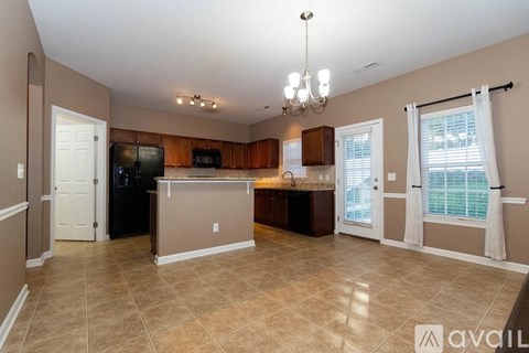 A kitchen with a refrigerator, microwave, and a dining table with chairs.