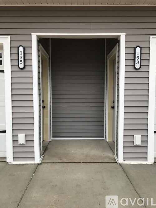 A grey house with a white door and a number 133 on the wall.