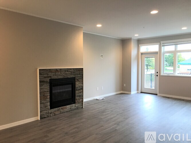 A living room with a stone fireplace and hardwood floors.