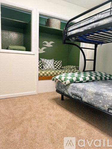 A bedroom with a bunk bed and a green accent wall.