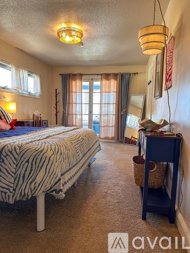 A bedroom with a bed, desk, and window.