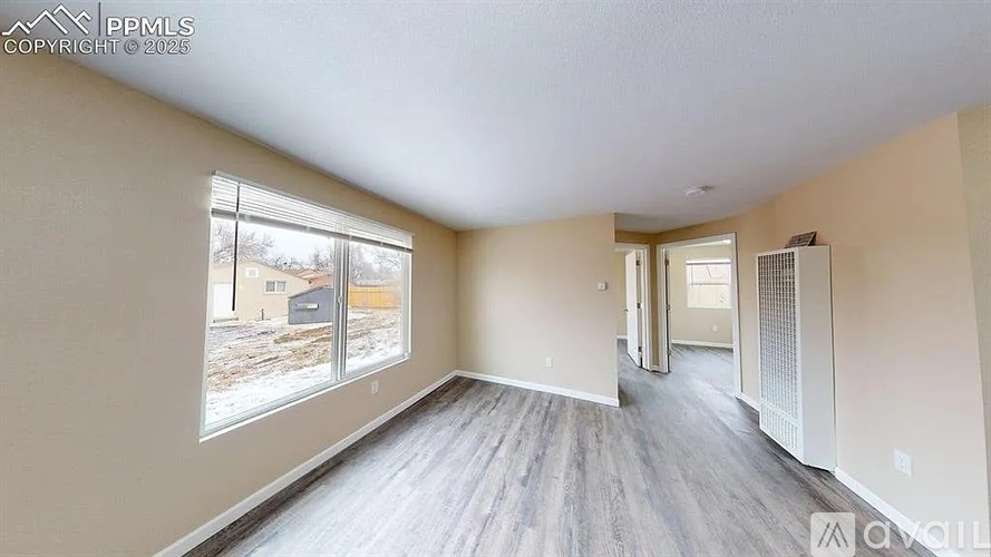 A spacious room with a view of a snowy landscape outside the window.