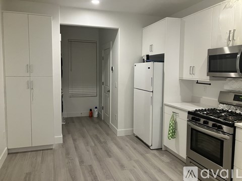 A kitchen with white cabinets and a grey floor.