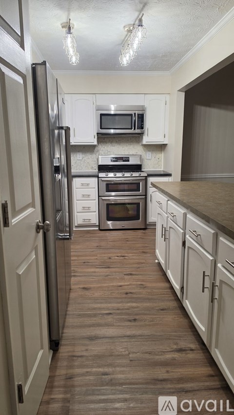A kitchen with white cabinets and a wooden floor.