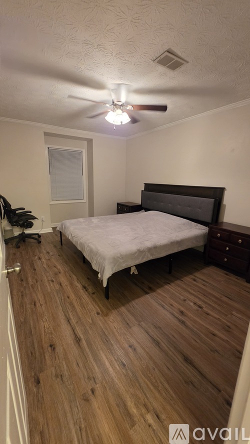 A bedroom with a bed, dresser, and ceiling fan.