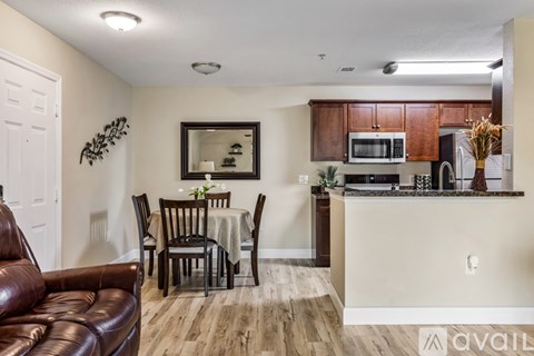 A kitchen area with a brown leather couch and a dining table with chairs.