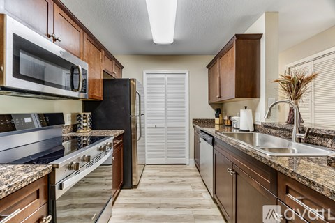 A kitchen with brown cabinets and a black refrigerator.