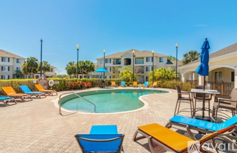 A pool area with sun loungers and a table with chairs.