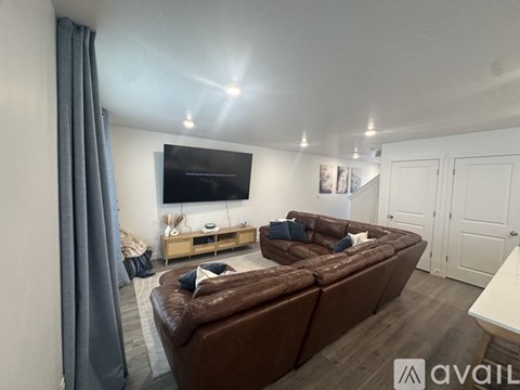 A living room with a brown couch and a flat screen TV mounted on the wall.