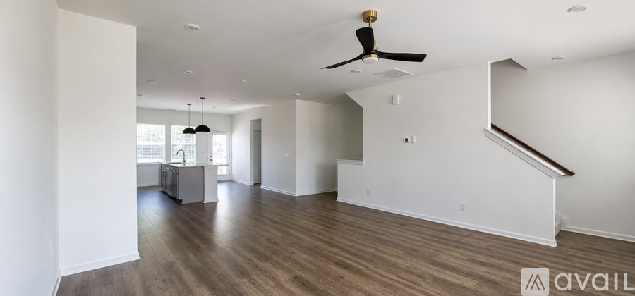 A spacious room with a staircase and a ceiling fan.