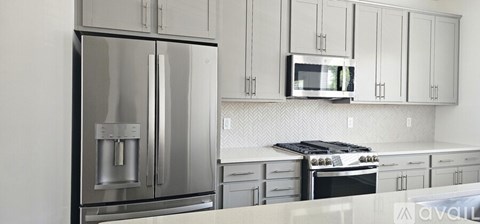 A kitchen with a stainless steel refrigerator and a microwave above the stove.