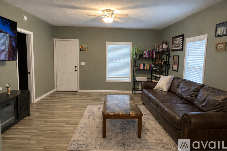 A living room with a brown leather couch, a wooden coffee table, and a flat-screen TV mounted on the wall.