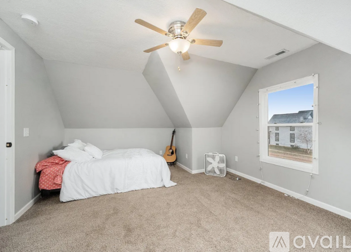 A bedroom with a bed, guitar, and window.